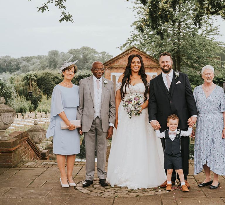 Bride and groom stand with their parents for a special family photo