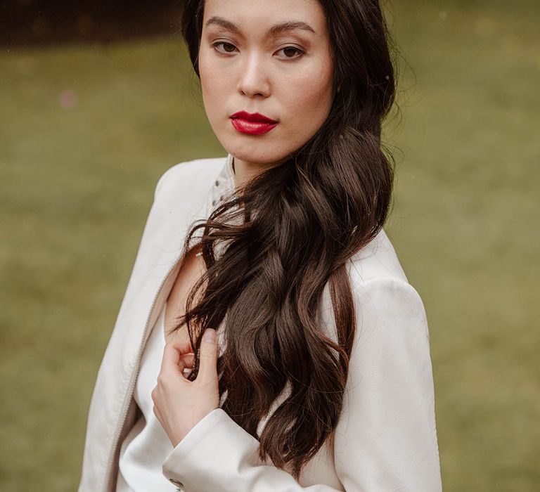 East Asian bride in a white bridal coverup and satin slip wedding dress with long wavy hair and red lipstick