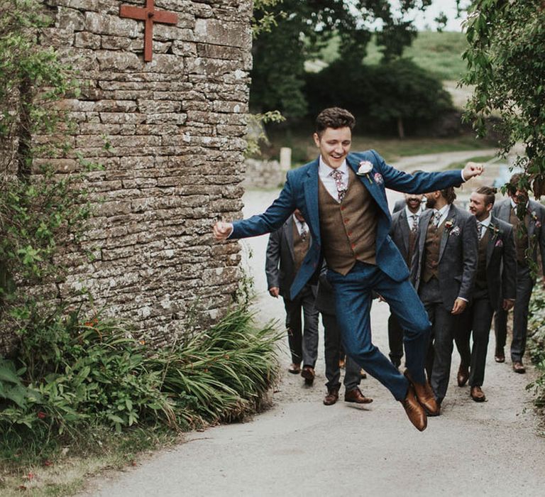 Groom in a blue suit and floral tie jumps up 