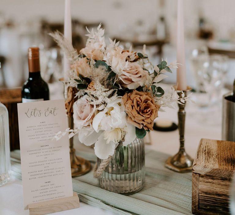 Wedding menu with small orange and white flower arrangement with white taper candles 