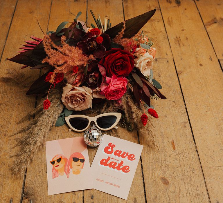 Pink and red wedding bouquet with retro style stationery and sunglasses