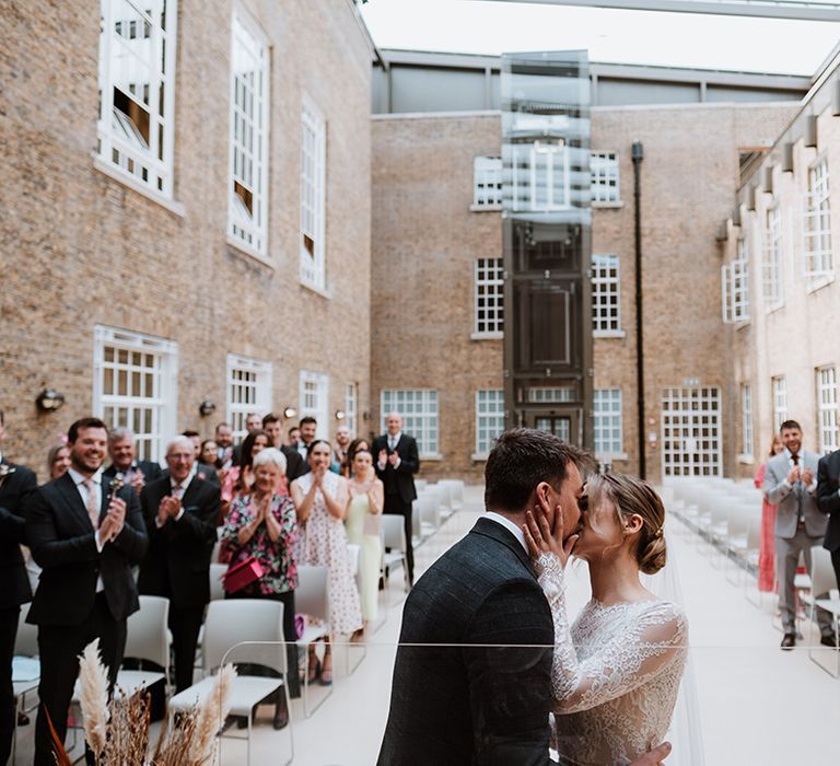 Bride in long sleeve Calla Blanche wedding dress kisses her groom during Hackney Town Hall wedding ceremony 