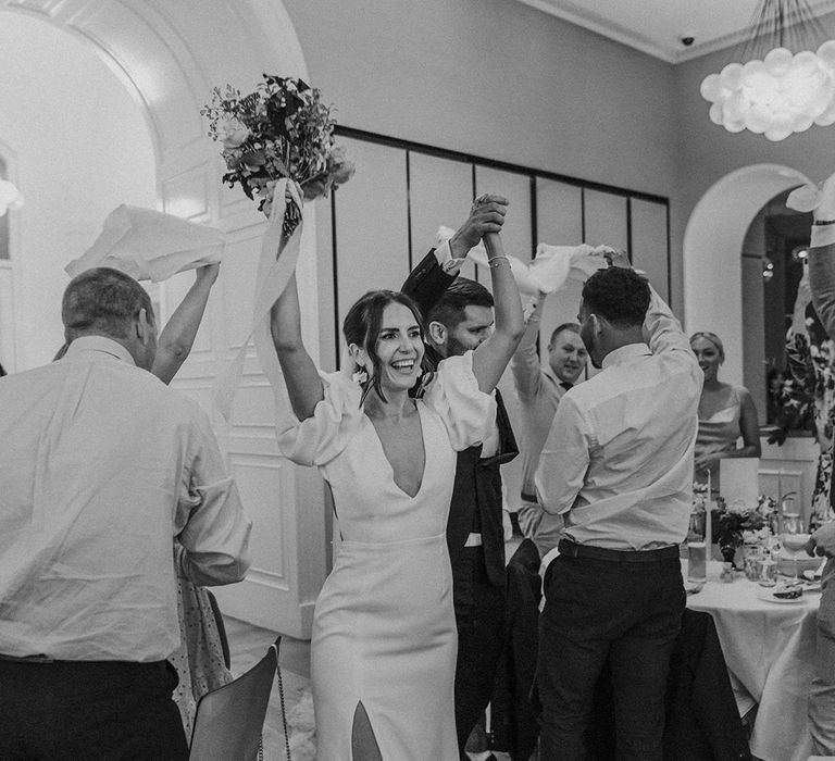 Bride in v neck wedding dress with front slit dancing with wedding guests at Somerset House