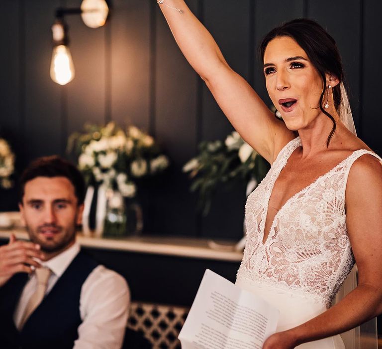 The bride holds up a microphone as she reads out her bridal speech