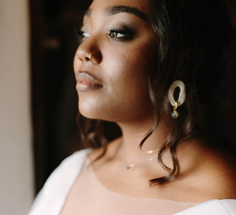 Detail shot of Bride's make up, jewellery and dress as she stares into the distance