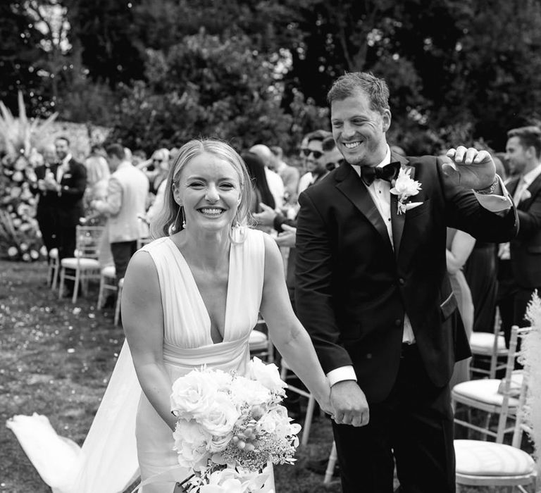 The bride and groom can't stop smiling as they walk back down the aisle at Pythouse Kitchen Gardens 