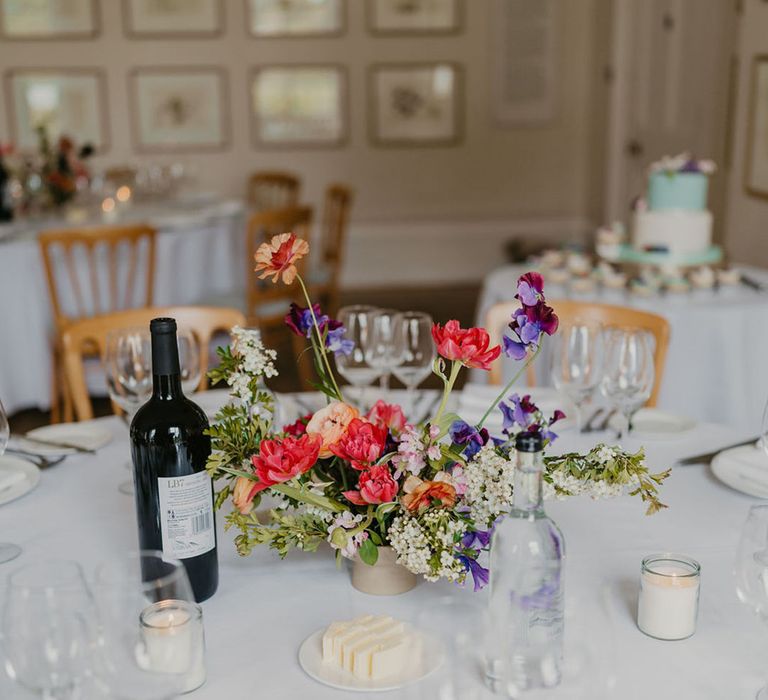 Brightly coloured floral centrepieces on round tables covered with white tablecloths 