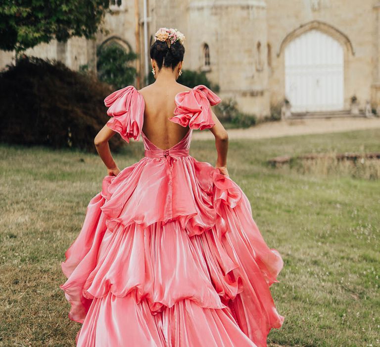 Bride wears shimmering pink Emma Beaumont wedding dress with ruffled styling and bow sleeves