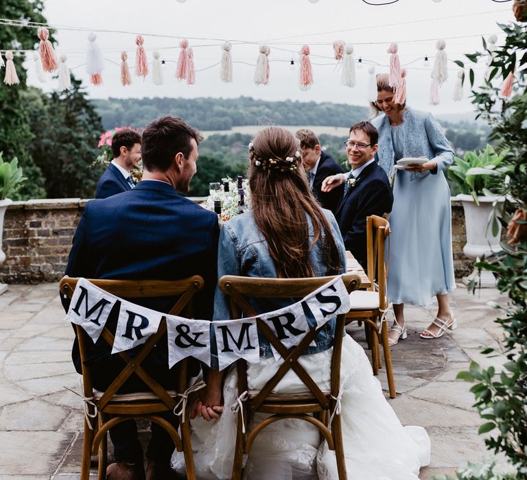 Black and white Mr & Mrs wedding banner decorating the dark wooden chairs for the bride and groom 