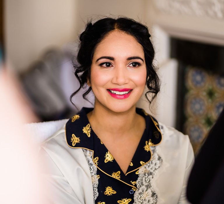 Bride wears fuchsia pink lipsticks and her dark hair tied into up-do with curled tendrils to the front 