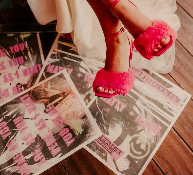 Bride wearing hot pink fluffy and strappy open-toe high heels sitting above tabloid newspaper wedding stationery 