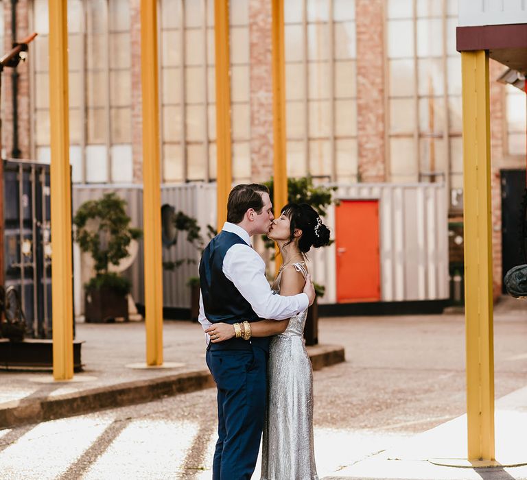 Bride in The Vampire's Wife wedding dress embraces her groom at Trinity Buoy Wharf industrial styled wedding venue