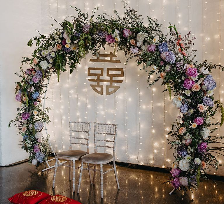 Fairy light curtain hangs behind pastel floral arch compete with Chinese double happiness sign