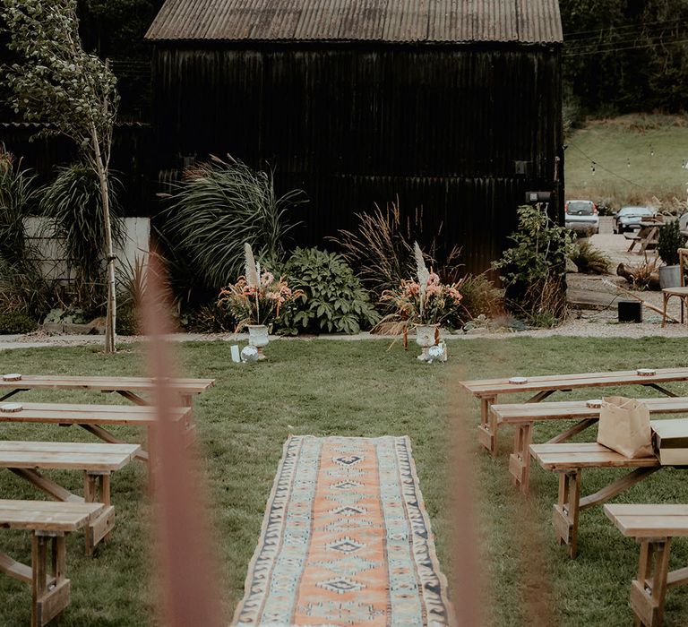 Rhyse Farm wedding wedding venue with dried pampas grass decor with Persian rugs lining the aisle for the outdoor wedding 