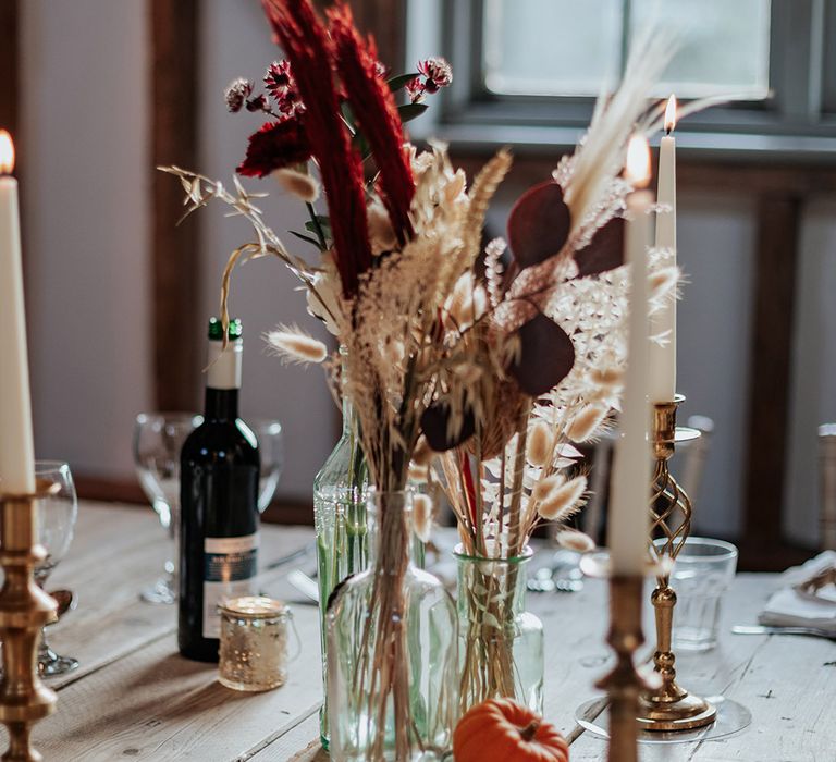 Dried wedding grass and flowers in glass vase with mini pumpkin decor for boho autumnal wedding at Milling Barn