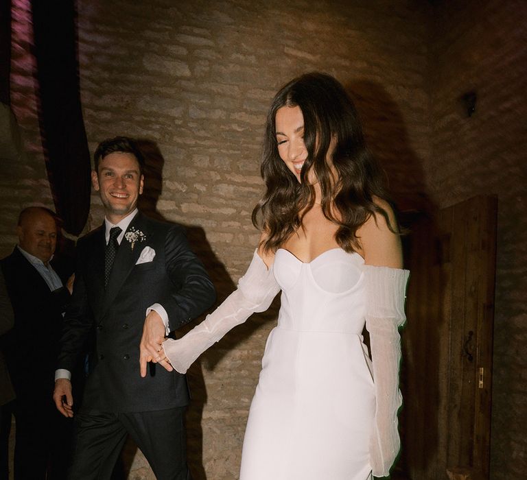 Bride wearing platform Jimmy Choo pearl shoes with matching pearl detachable sleeves with the groom in dark blue suit 