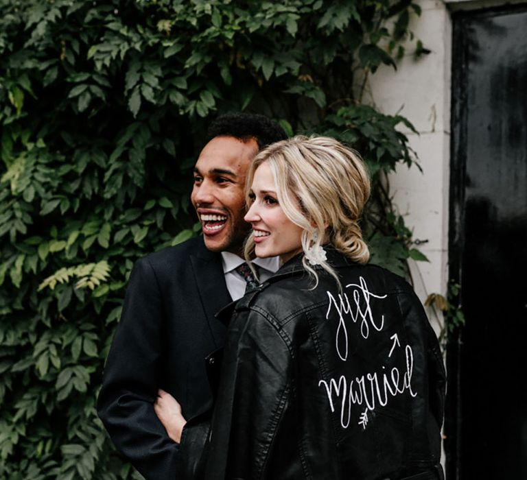 'Just Married' leather jacket smiling with the groom for the wedding 