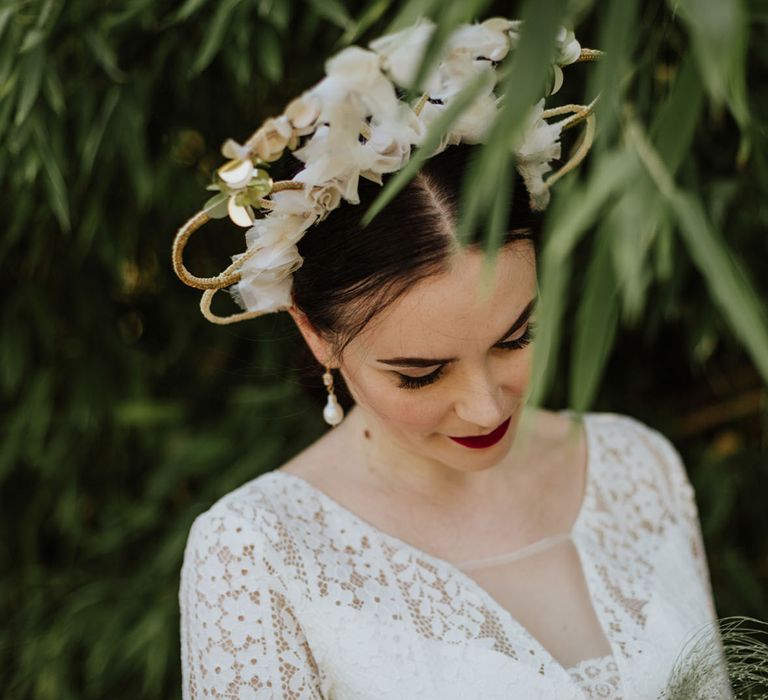 Structured bridal crown with white floral detailing on bride in lace wedding dress and red lip makeup