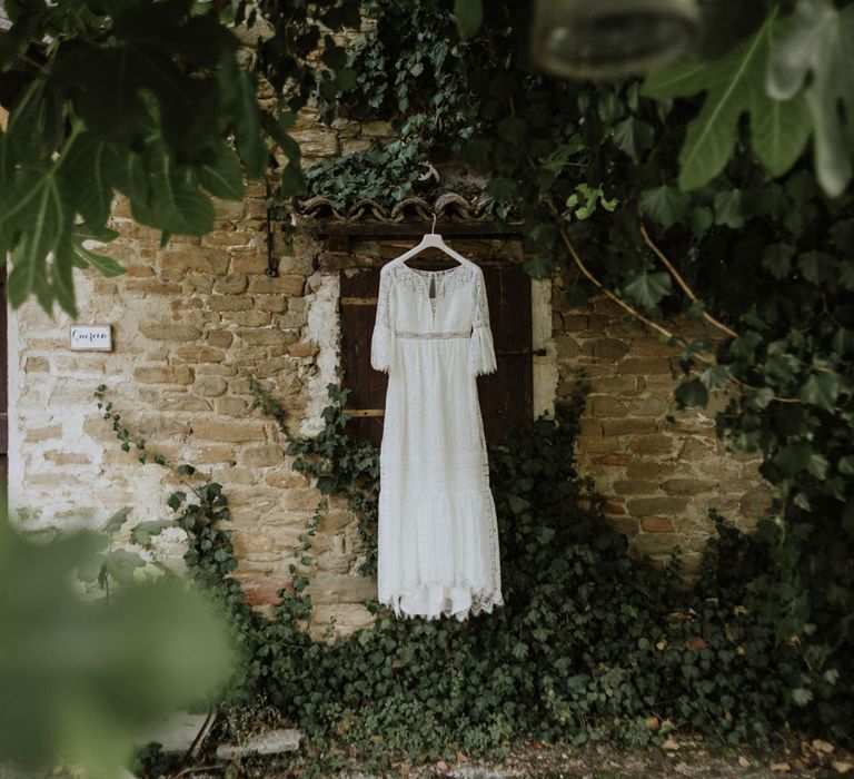 lace wedding dress hanging outside a rustic italian wedding venue surrounded by greenery