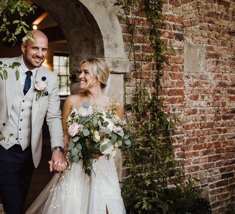 Groom in light grey three piece suit with the bride on their wedding day 