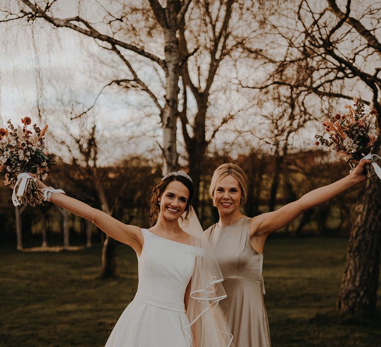 Maid of honour in high neck satin sage green bridesmaid dress with the bride in off the shoulder wedding dress for rustic romance theme wedding 