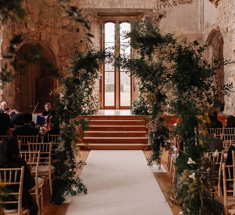 Flower columns lining the aisle and decorating the altar with yellow and white pastel flowers 