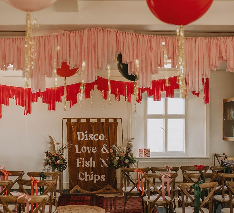 Pink, red and gol streamers and balloons decorating the lighthouse wedding venue with funny large wedding banner altar decoration 