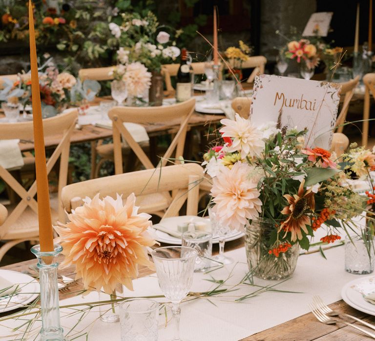 Orange theme table setting with soap wedding favours, cafe au lait dahlias, orange taper candles, blue napkins and white crockery 