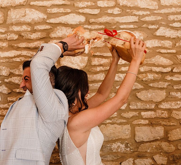 Bride and groom performing the breaking bread Bulgarian wedding traditions at their wedding breakfast 