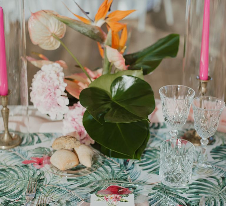 sweetheart table place setting with palm leaf table cloth and glass charger plate