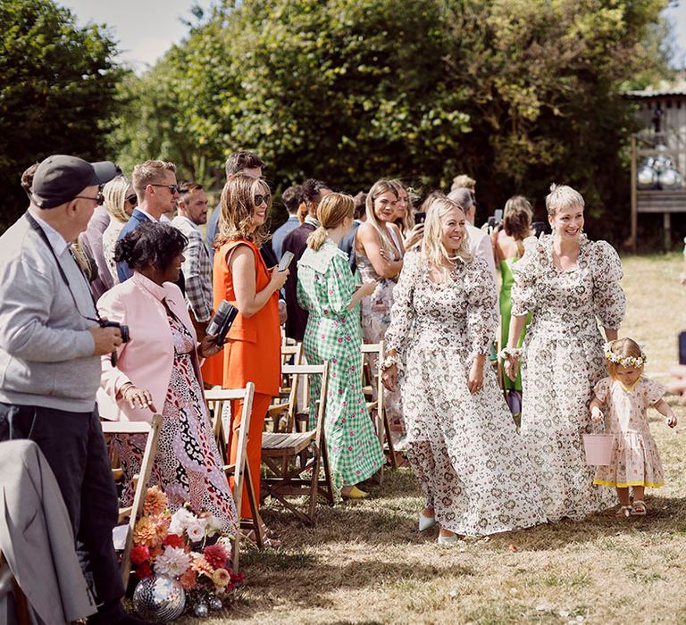 Bridesmaids in funky patterned puff sleeve bridesmaid dresses with little flower girl 