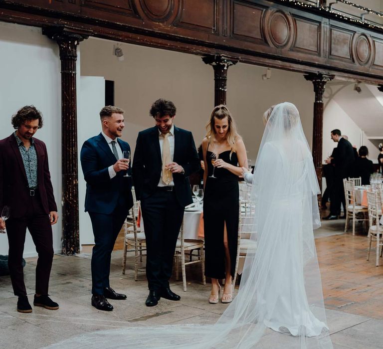 Bride in cathedral-length personalised and embroidered wedding veil talking to wedding guests at Fabrica Brighton wedding venue