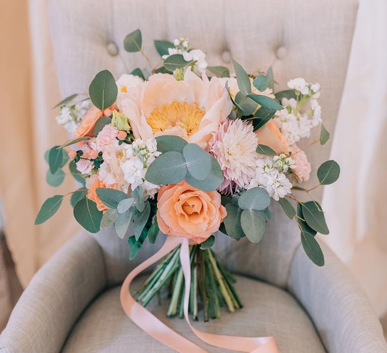 Peach, coral, and white neutral wedding bouquet for the bride tied with ribbon 