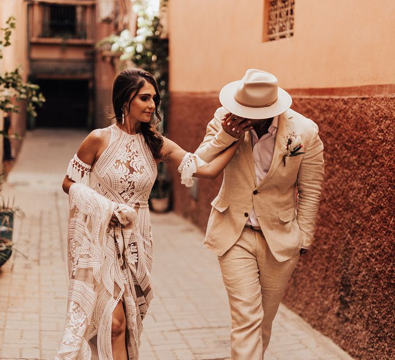 The bride wears a lace bridal gown with the groom wearing a wedding hat that matches the suit 