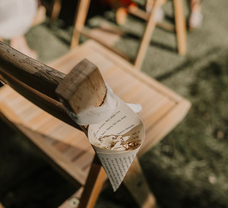 Confetti cones made up of book pages full of confetti on the end of every aisle seat 