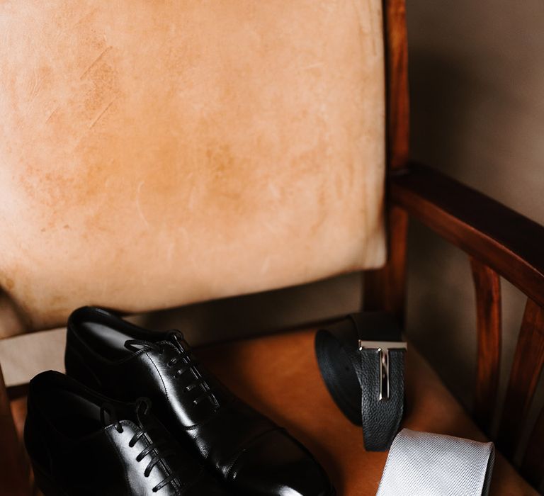 Groom's accessories with black shiny leather shoes, Ted Baker belt, and light silvery grey tie 