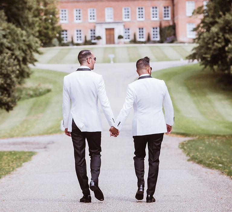 Two grooms walking together at their same sex gay wedding in Essex 