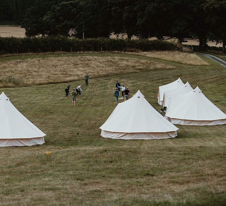 White bell tents for guests to sleep in at rustic wedding venue 