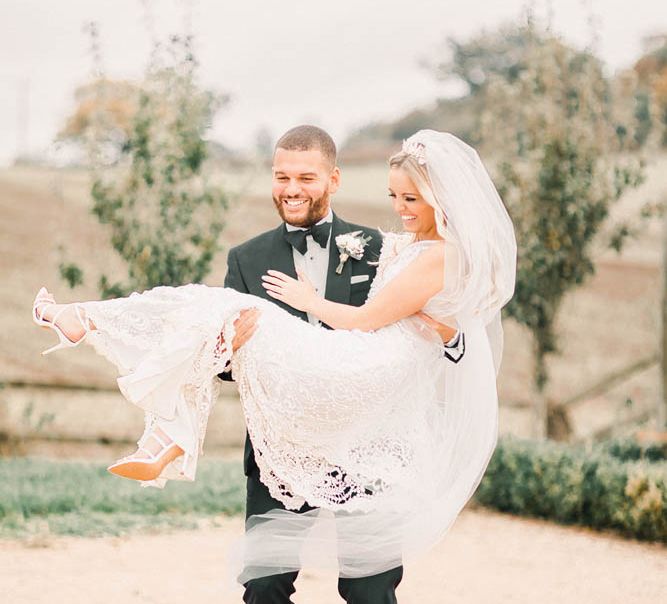 Groom picking his bride up at black tie winter wedding 