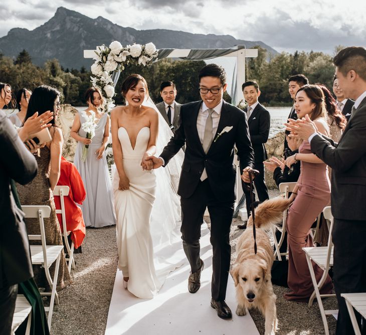 Bride and groom descending down the aisle with their pet dog 