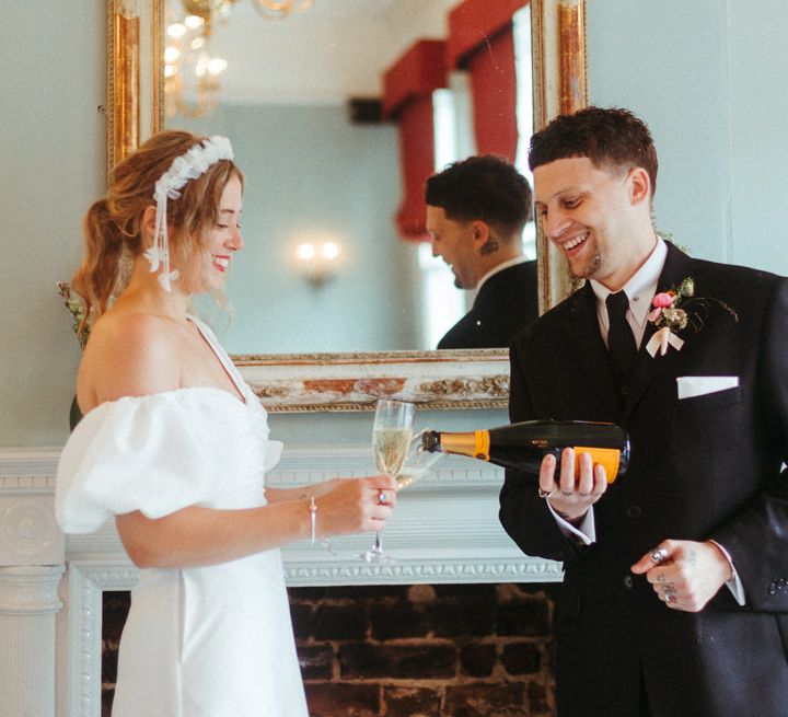 Bride and groom toast to their marriage in front of fireplace