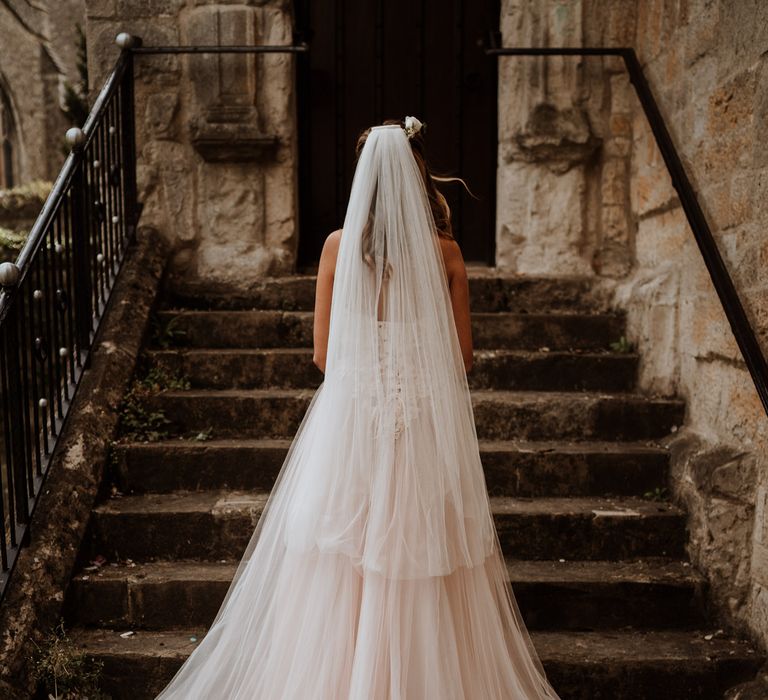 Bride in blush tulle wedding dress standing on the steps 