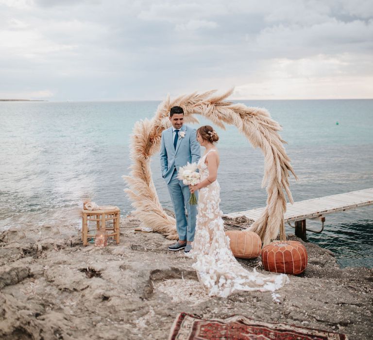 Bride and groom at pink and blue wedding with pampas grass moon gate