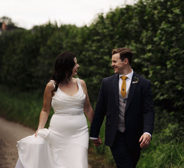 Bride & groom walk together in the countryside 