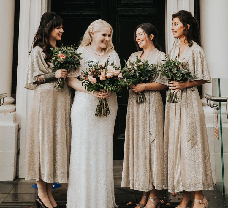 Bride poses with her bridesmaids holding floral bouquets 