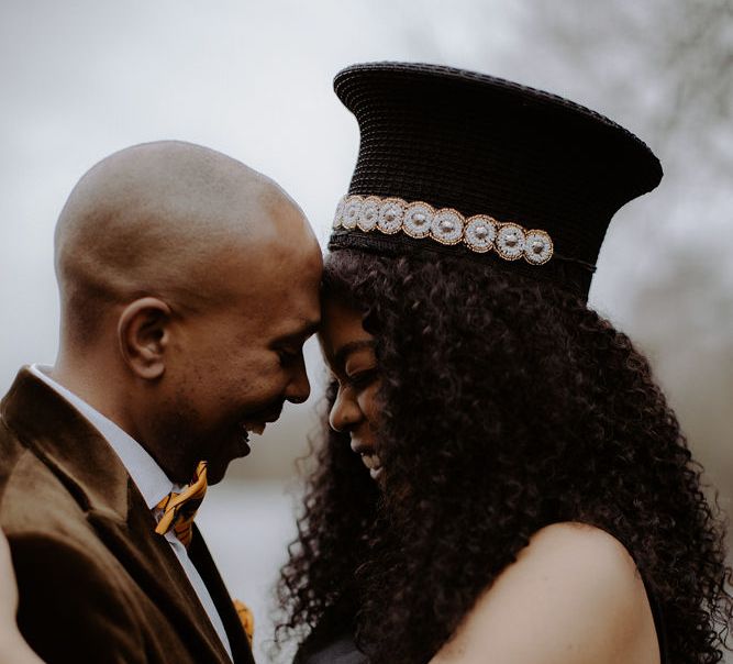 Groom in brown velvet blazer and bride in handmade Zulu hat