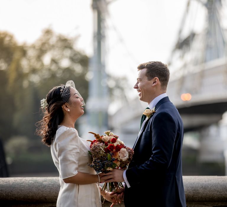 Bride in Ba&sh registry wedding dress and birdcage veil holding a red wedding bouquet 