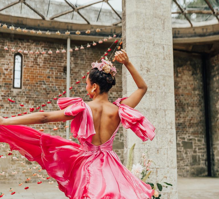 A bride twirls in a bright pink dress 