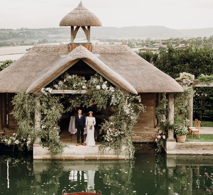 Bride in Elbeth Gillis gown holds hands with groom under roof at Euridge Manor Orangery 