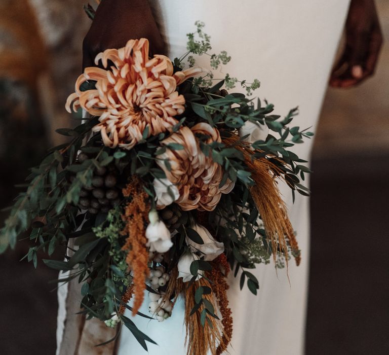 Orange and green wedding bouquet with flowers, foliage and dried grasses 